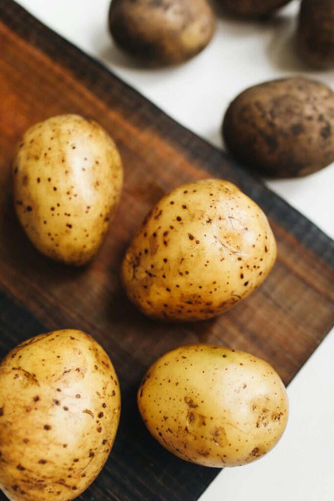 Close-up of fresh potatoes on a wooden board, highlighting their natural texture.